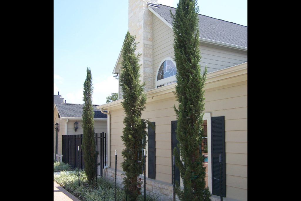 An image of the Northland Woods property clubhouse. There are three tall, skinny bushes next to it.