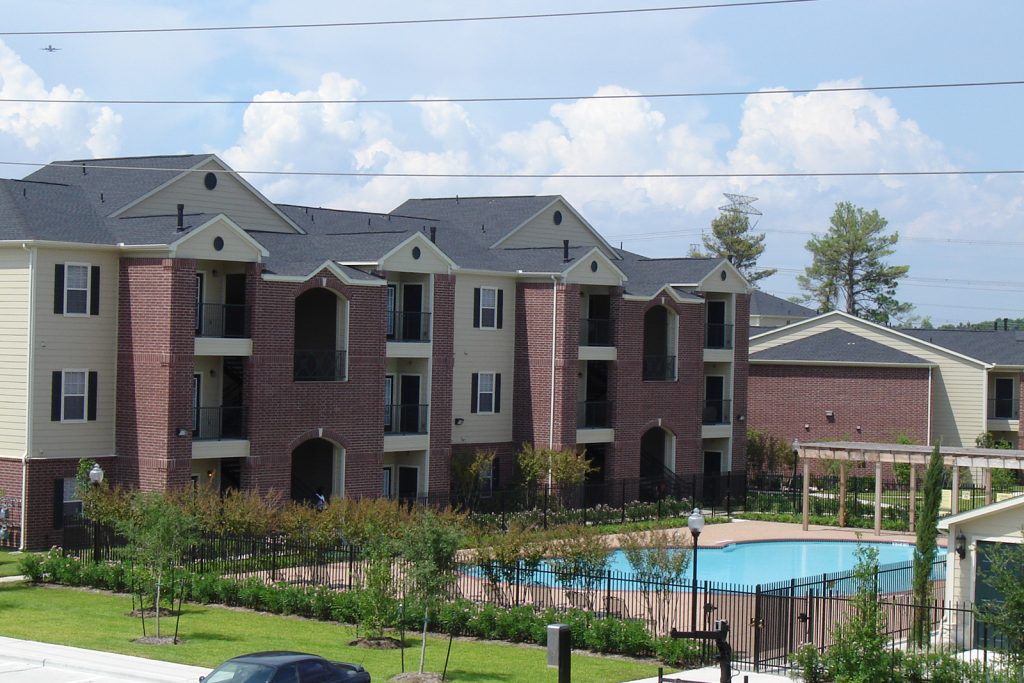 A zoomed out image of one of the Northland Woods apartment buildings next to the gated property pool.